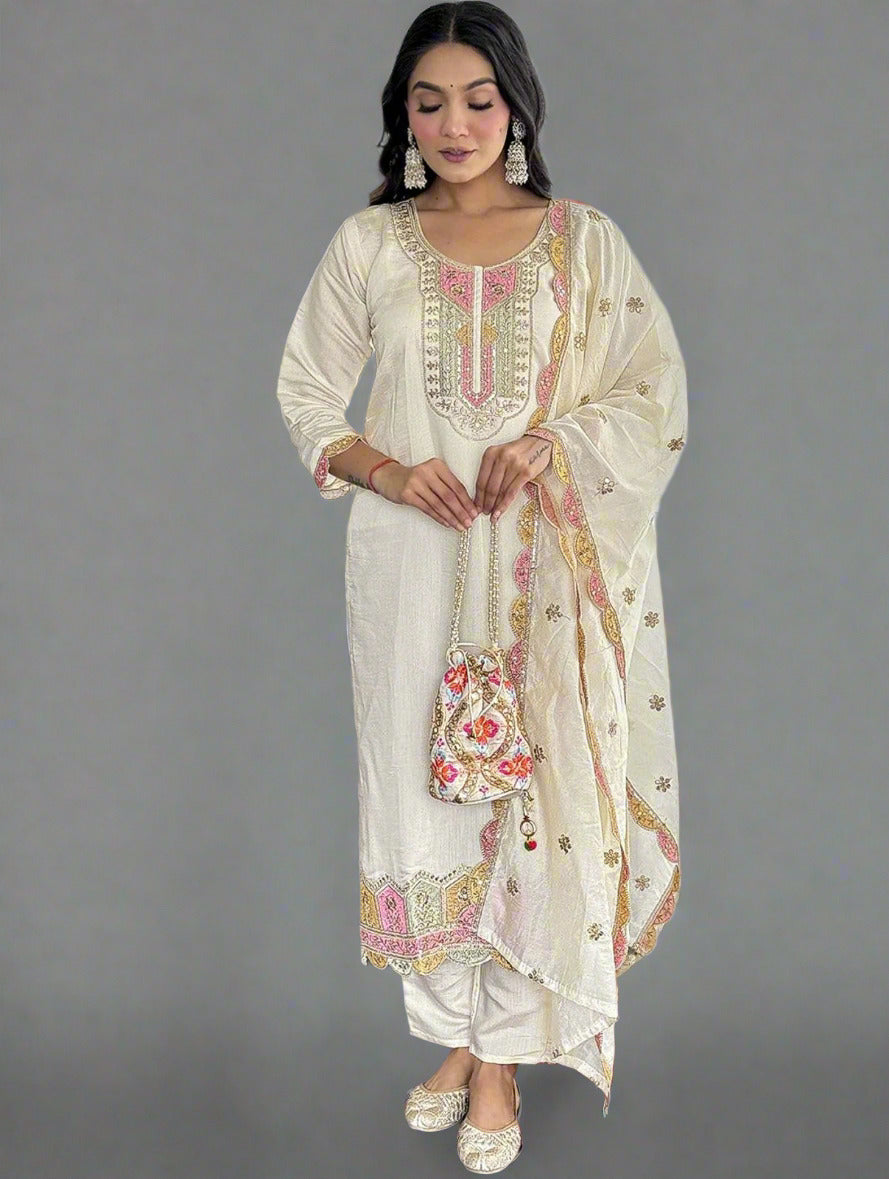 Woman in a cream embroidered outfit standing in front of a mirror.